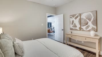 A bedroom with a bed, a console table, and abstract wall art.
