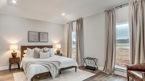 Un dormitorio con una cama grande, dos lámparas de noche, vistas al exterior y una ventana con cortinas.