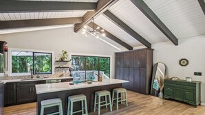 A modern kitchen with a large island, dark cabinets, and a view of the outdoors. - Modern Forest Escape, Near Lake Stevens & Hikes (Lake Stevens)