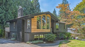 A modern two-story house with large windows, a wooden deck, and a stone chimney. - Modern Forest Escape, Near Lake Stevens & Hikes (Lake Stevens)