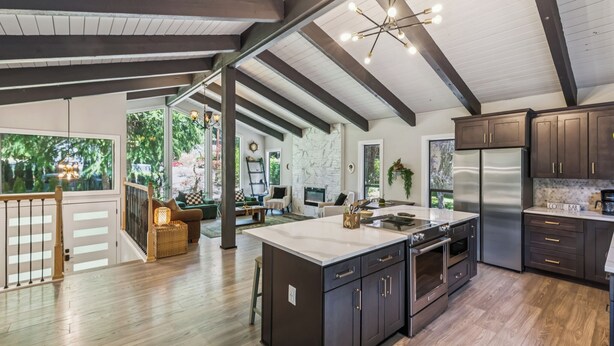 A spacious kitchen with dark cabinetry, a large island, and a stainless steel refrigerator. - Modern Forest Escape, Near Lake Stevens & Hikes (Lake Stevens)