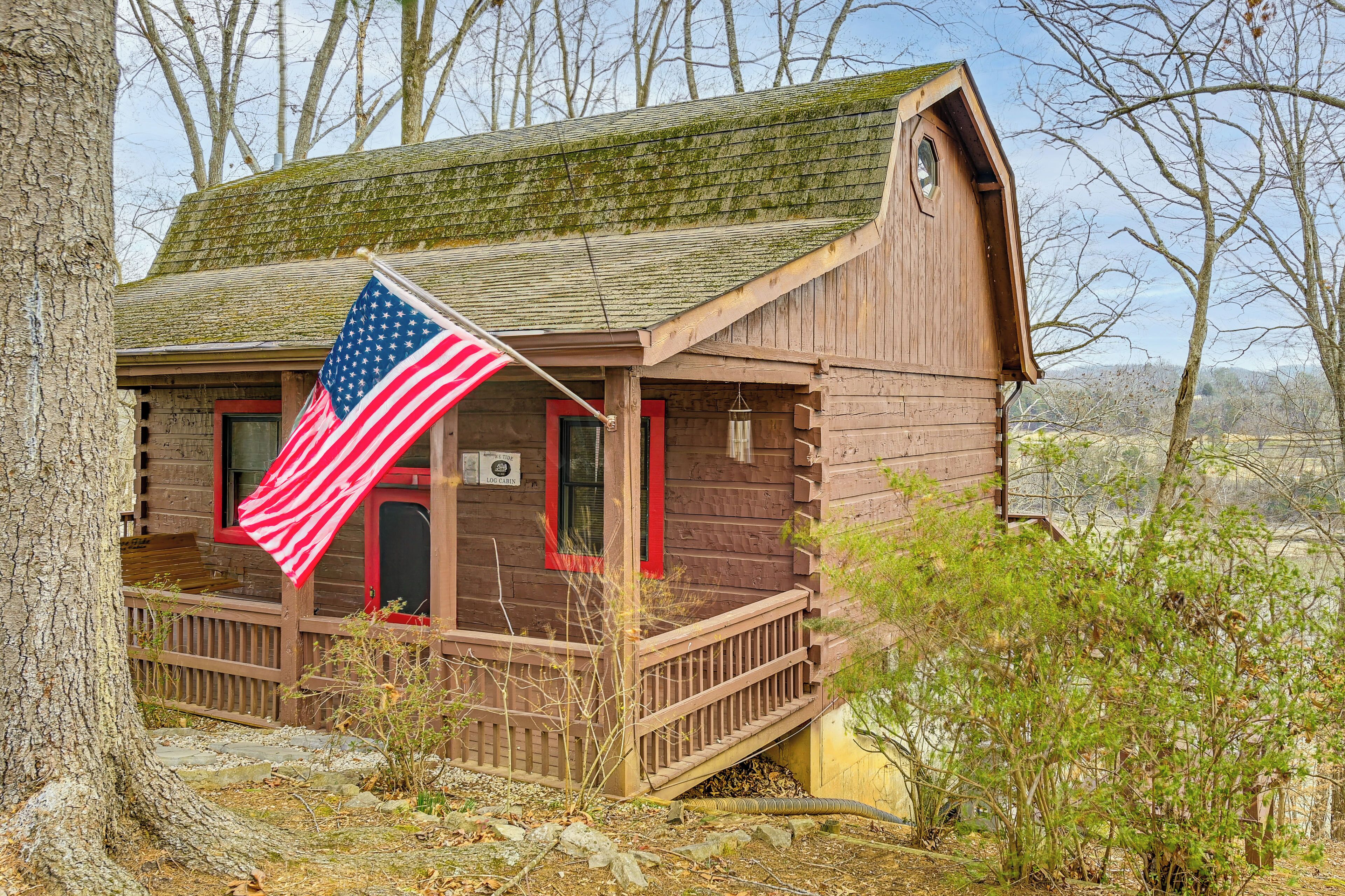 A wooden cabin with a porch, a flag, and a small window.