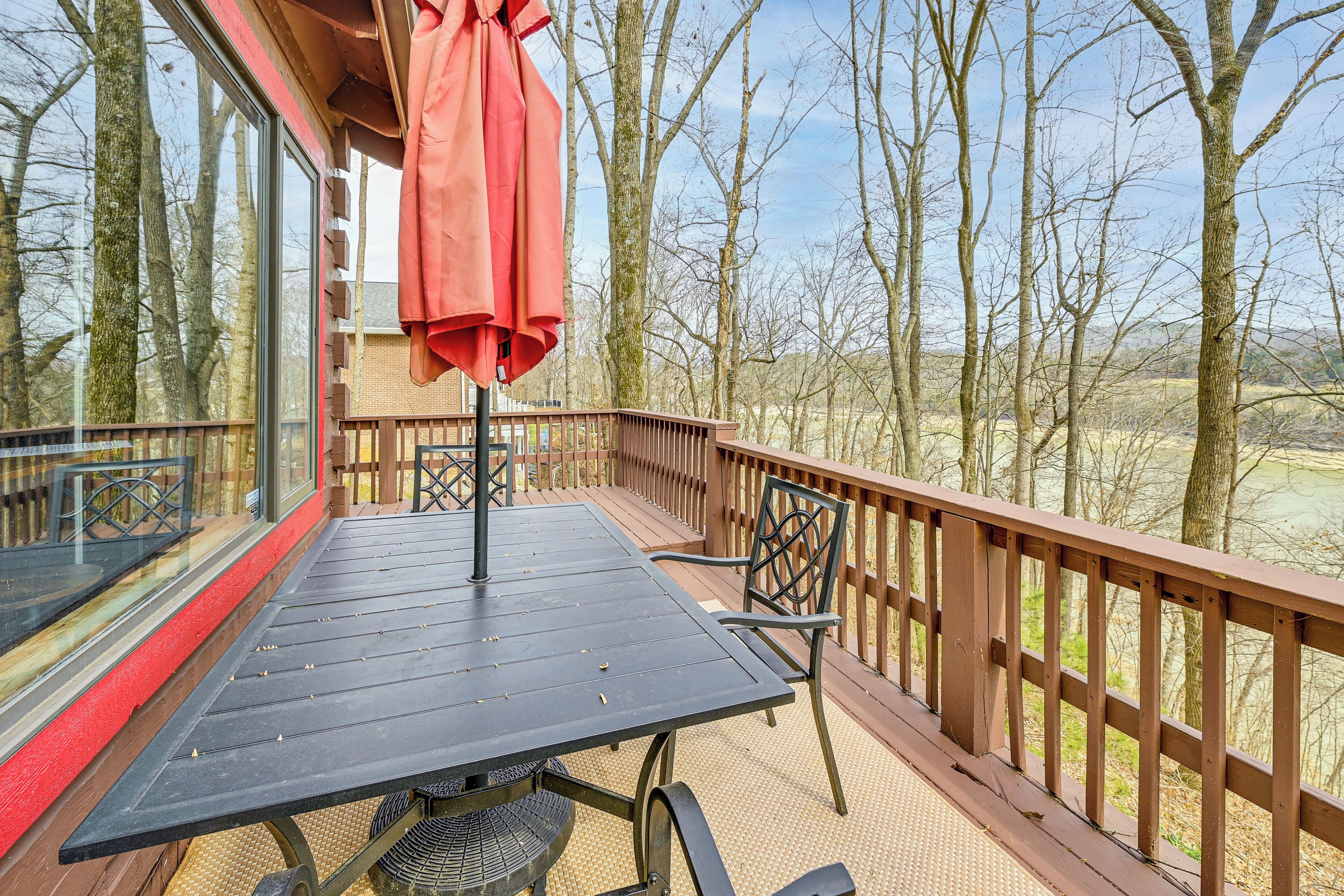 A wooden deck with a table and chairs, overlooking a forested area.