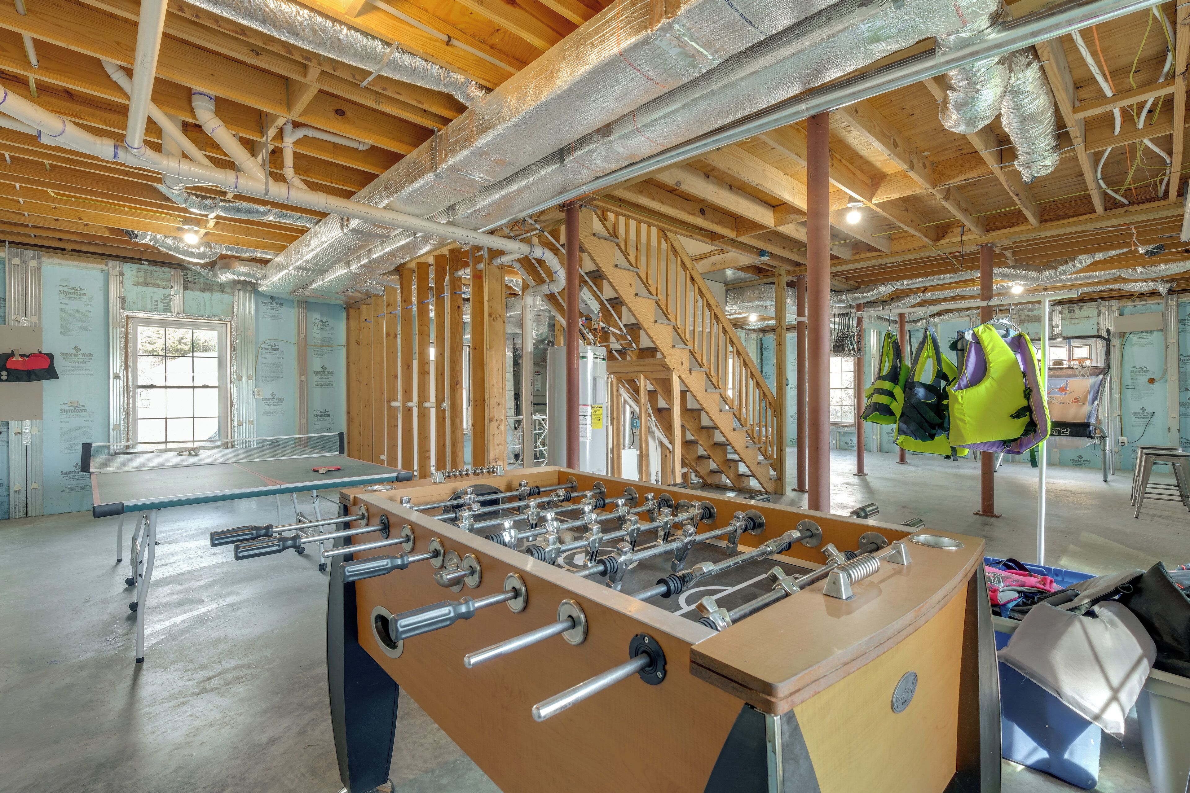 A spacious room with exposed wooden beams, a foosball table, and a staircase.