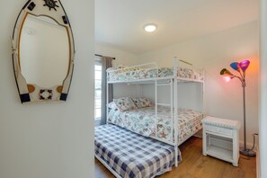 Ein Etagenbett mit floraler Bettwäsche, ein kleiner Nachttisch und ein Spiegel im maritimen Stil.
