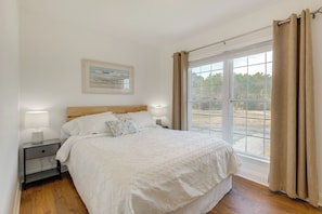 A bedroom with a bed, bedside tables, and a window with curtains. - Waterfront Gem w/ Deck & Views on Chesapeake Bay! (Reedville)
