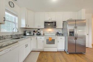 Une cuisine moderne avec des meubles blancs, un réfrigérateur en acier inoxydable, un four à micro-ondes, une cuisinière et un évier.