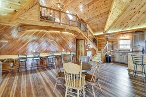 A wooden interior with a dining area, kitchen, and a staircase leading to an upper level. - Steps to Private Beach! Family Home on Lake James (Morganton)