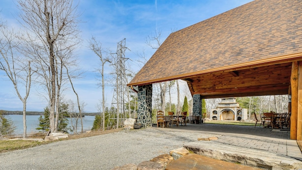 A lodge with a stone facade, outdoor seating, and a view of a lake. - Steps to Private Beach! Family Home on Lake James (Morganton)