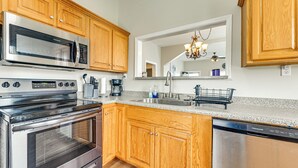 A modern kitchen with wooden cabinets, stainless steel appliances, a granite countertop, and a large mirror above the sink. - Lake Days & Fireside Nights! Updated Burnside Home (Burnside)