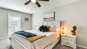 A bedroom with a bed, a nightstand, a ceiling fan, and a window with blinds. - Lake Days & Fireside Nights! Updated Burnside Home (Burnside)