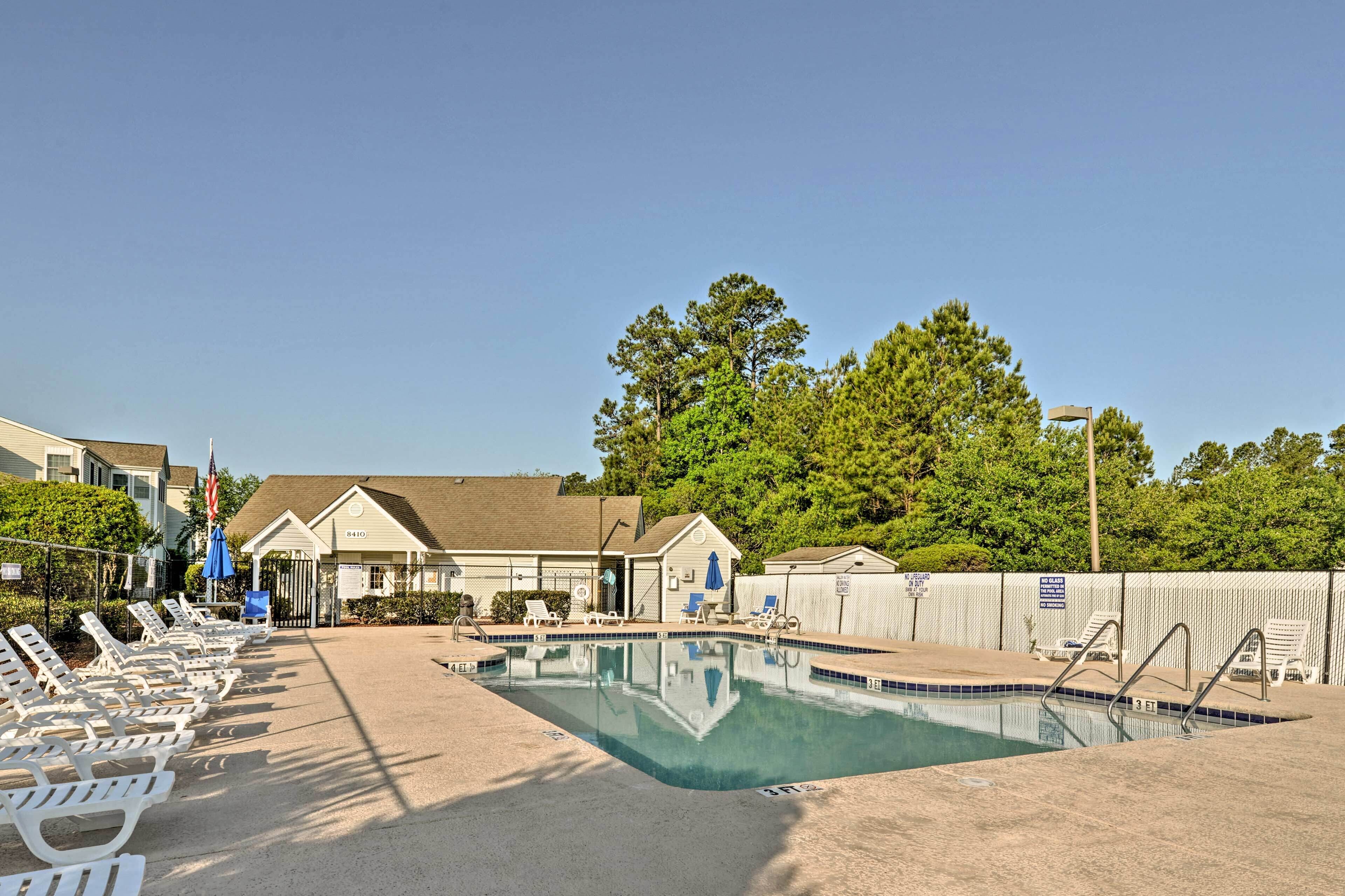 A swimming pool with lounge chairs, a covered area, and a building with a sign.