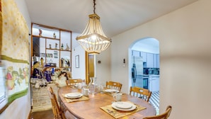 A dining area with a wooden table, chairs, a chandelier, and a view into the kitchen. - Pool Table & Shared Sauna! Potomac River Basecamp (Westernport)