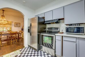 A kitchen with a refrigerator, stove, microwave, and a dining area with wooden chairs and a chandelier. - Pool Table & Shared Sauna! Potomac River Basecamp (Westernport)