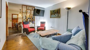 A living room with a sofa, armchair, wooden coffee table, and a flat-screen TV mounted on the wall. - Pool Table & Shared Sauna! Potomac River Basecamp (Westernport)