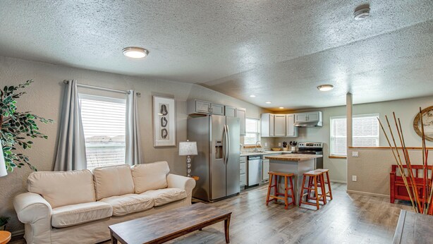 A modern kitchen with stainless steel appliances, a dining area with a wooden table and bar stools, and a living room with a sofa and a coffee table. - Mountain Basecamp Near Red Rocks (Golden)