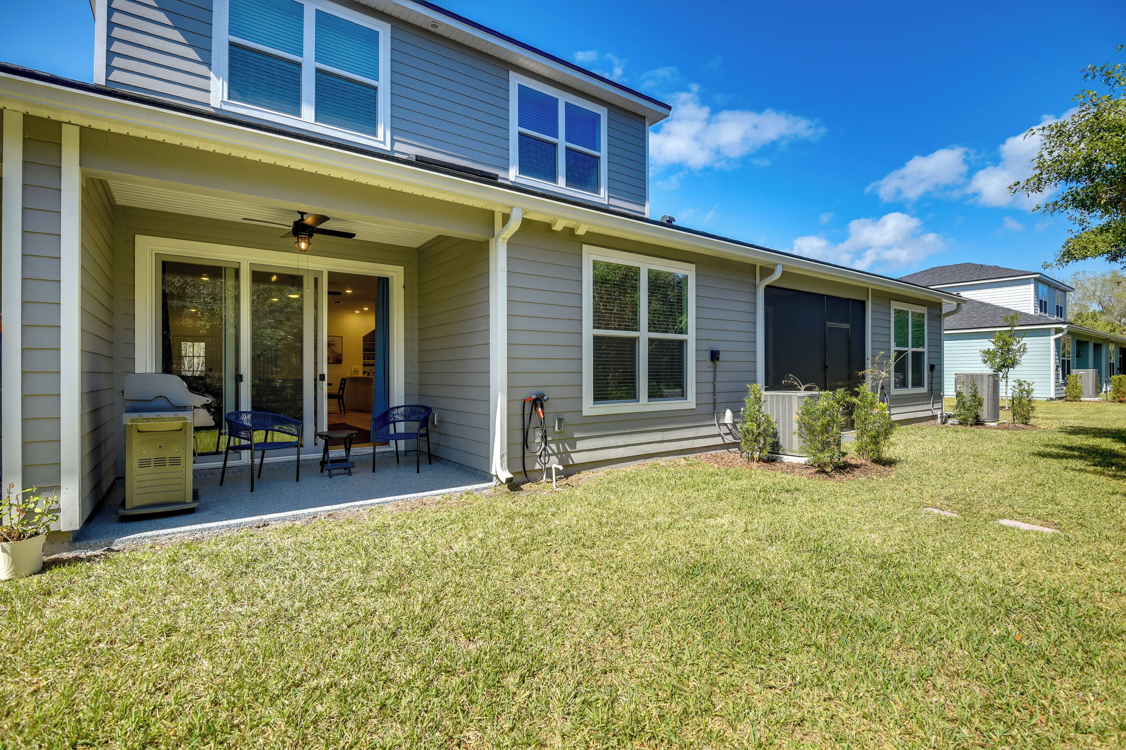A two-story house with a covered patio, a grill, and a small garden.
