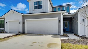 A two-story house with a garage, a front door, and a small porch. - Beach, Eats, Shops! Sunny Stay By European Village (Palm Coast)