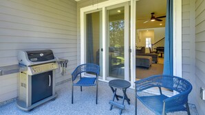 A covered patio area with a grill, two blue chairs, and a table. - Beach, Eats, Shops! Sunny Stay By European Village (Palm Coast)