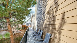 A row of outdoor chairs aligned against a building with horizontal siding. - Mountain Basecamp Near Red Rocks (Golden)