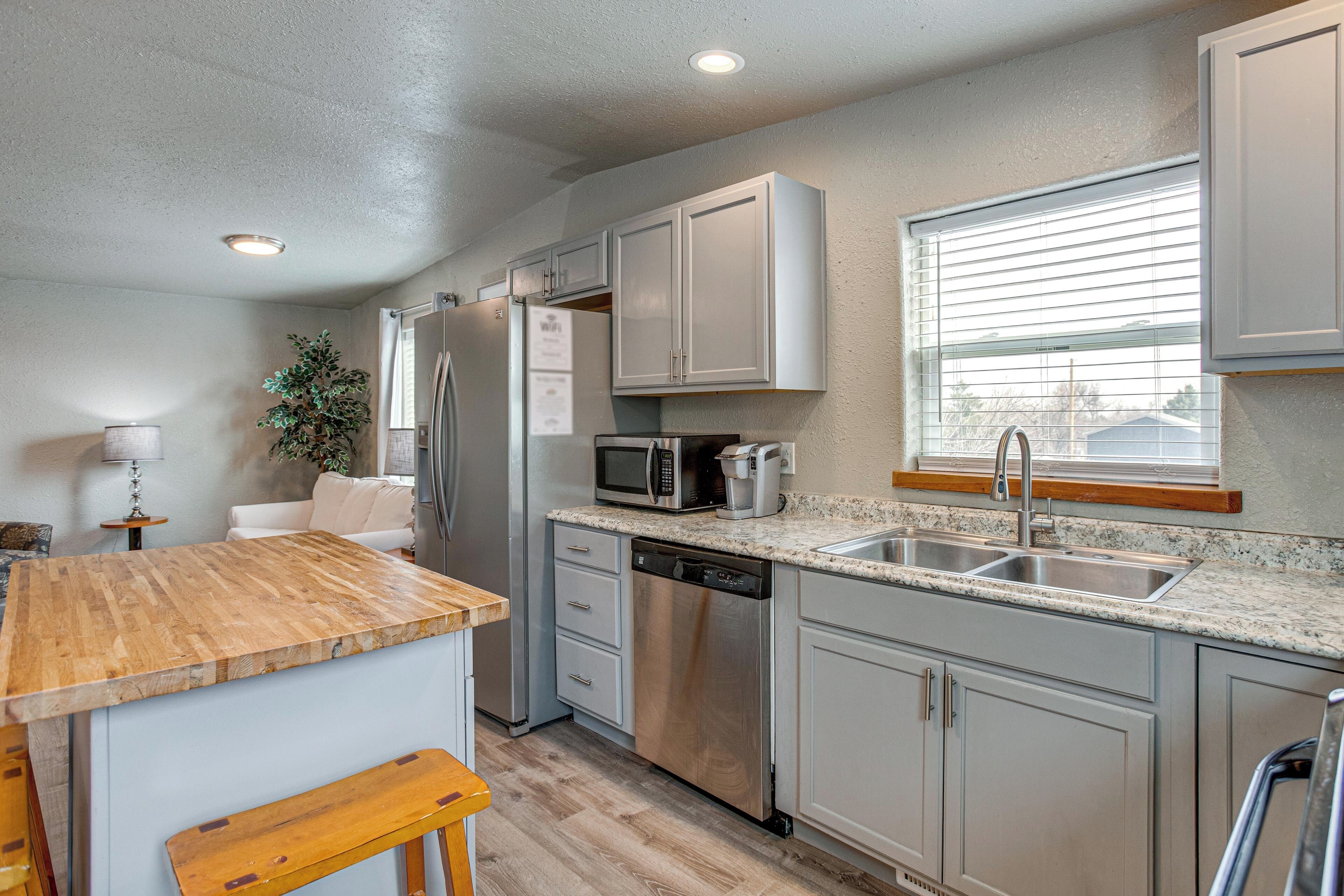 A modern kitchen with a wooden island, stainless steel appliances, and a window with blinds.