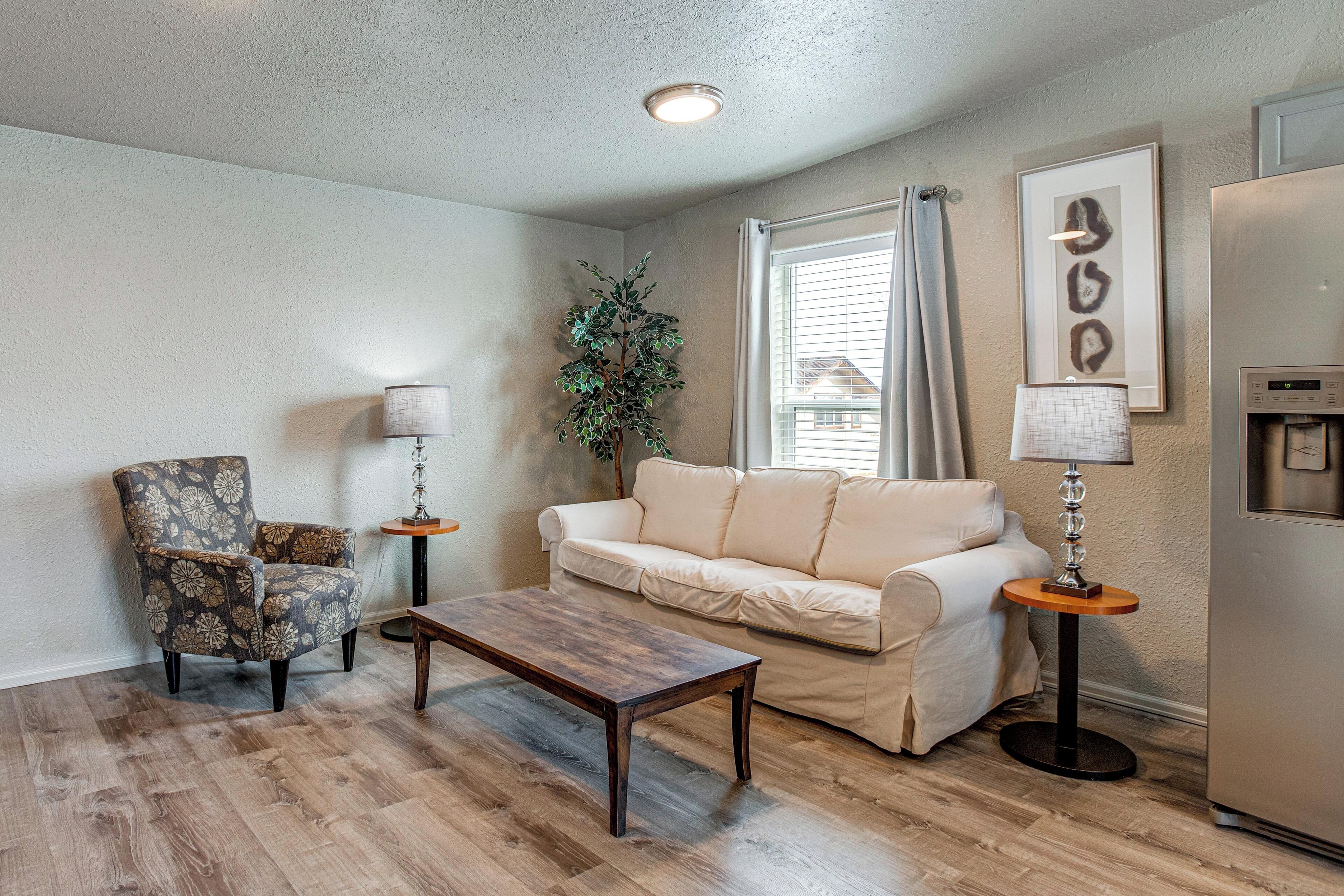 A living room with a sofa, armchair, coffee table, and two side tables with lamps.