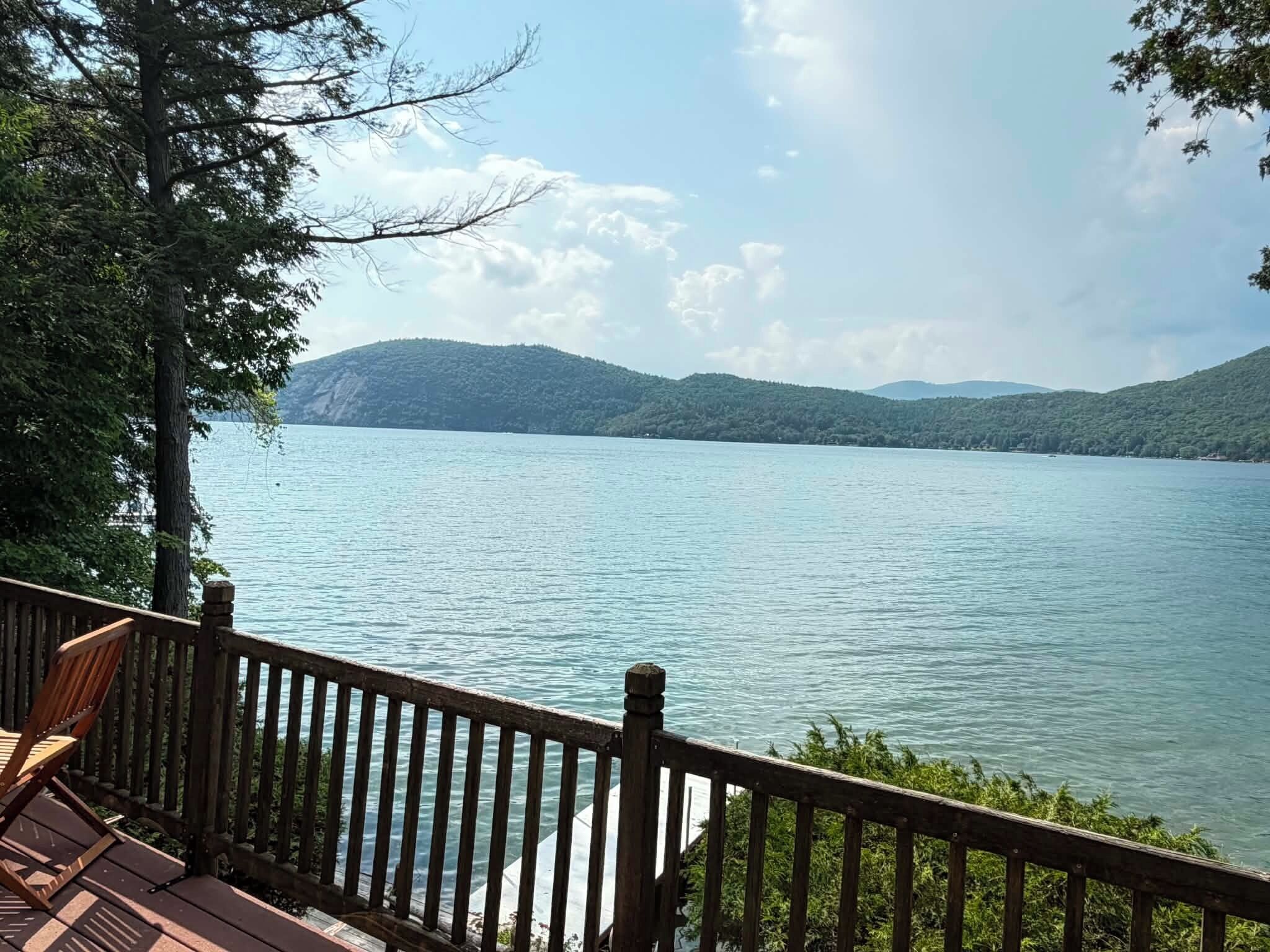 Une terrasse en bois offrant une vue sur un lac paisible et des montagnes lointaines.