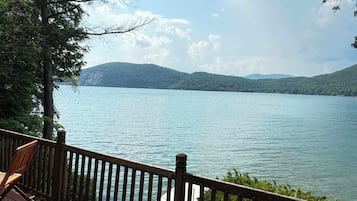 Une terrasse en bois offrant une vue sur un lac paisible et des montagnes lointaines.