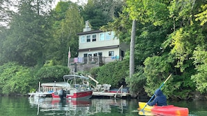 Ein Haus mit Steg und Booten, umgeben von dichtem Grün.