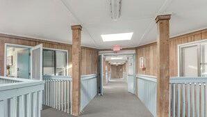 A corridor with wooden paneling, a patterned carpet, and a ceiling light. - Steps to Sand! Pool-view Retreat in Myrtle Beach (Myrtle Beach)