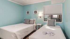 A room with two beds, a ceiling fan, a window with blinds, and wall-mounted light fixtures. - Steps to Sand! Pool-view Retreat in Myrtle Beach (Myrtle Beach)