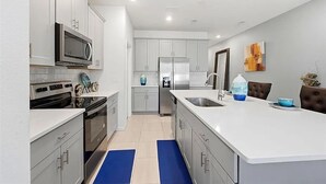 Une cuisine moderne avec des armoires blanches, des appareils en acier inoxydable et un îlot central.