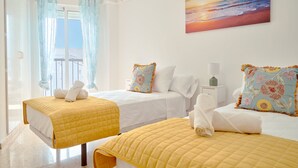Ett hotellrum med två sängar, en balkong med utsikt och en målning som föreställer en solnedgång.