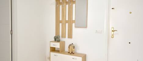 A minimalist bedroom with a wooden vanity, a mirror, and a door with a brass handle.