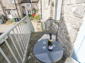 A balcony with a table, a bottle of wine, and two glasses.