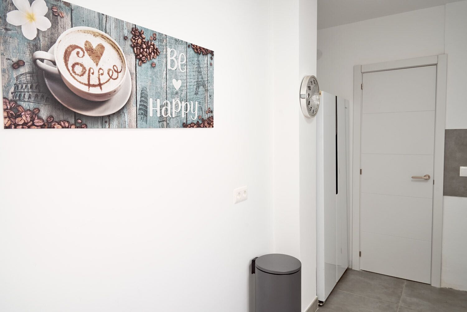 Un passadís amb un cartell fixat a la paret que mostra una tassa de cafè i la frase "Be Happy".