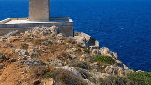A lighthouse on a rocky outcrop with a clear view of the sea.