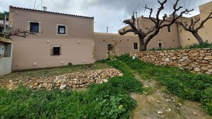 A traditional building with a stone wall and a tree in the courtyard. - Conastasia - Concona Houses (Rethymno)