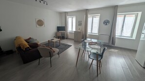 A modern living room with a sofa, coffee table, and dining table with chairs.