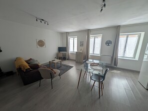 A modern living room with a sofa, coffee table, and dining table with chairs.