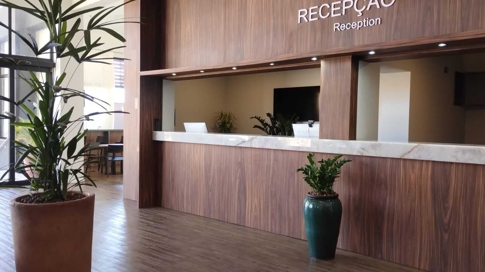 A reception area with a wooden reception desk, potted plants, and a modern interior design.