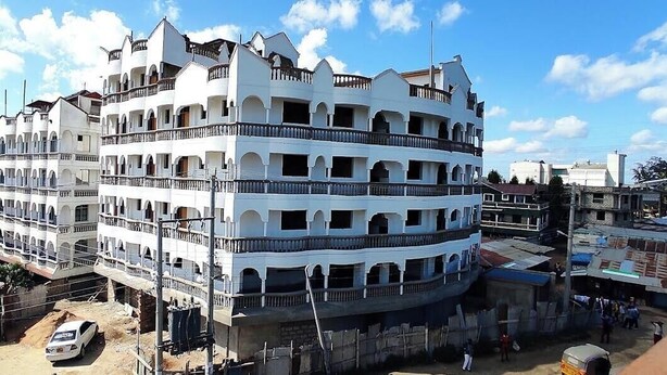 A multi-story building with balconies, a courtyard, and a mix of residential and commercial structures nearby. - White Castle Hotel Mikindani (Mombasa)
