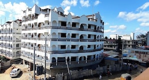 Un edifici de diverses plantes amb balcons, un pati interior i una barreja d'edificis residencials i comercials a prop.