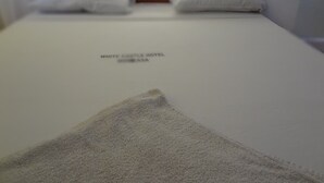 A neatly made bed with a white sheet and two pillows, a white blanket, and a sign reading "WHITE CASTLE HOTEL MOMBASA". - White Castle Hotel Mikindani (Mombasa)