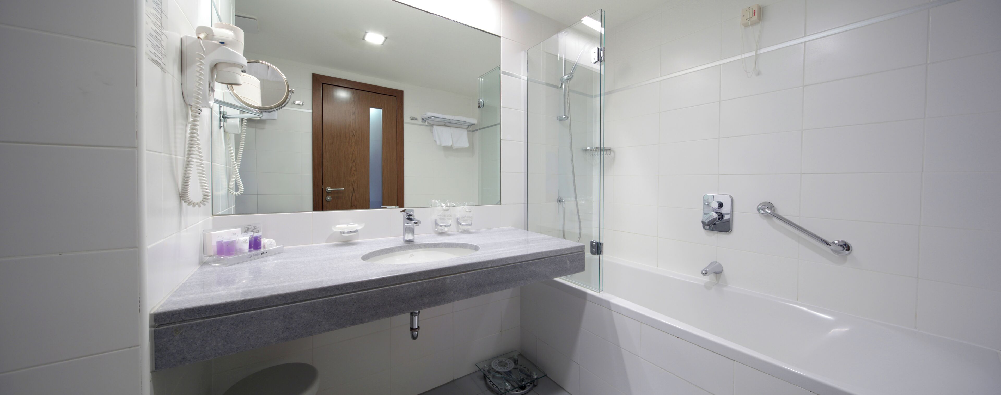 A modern bathroom with a marble sink, a glass-enclosed shower, and a large mirror.