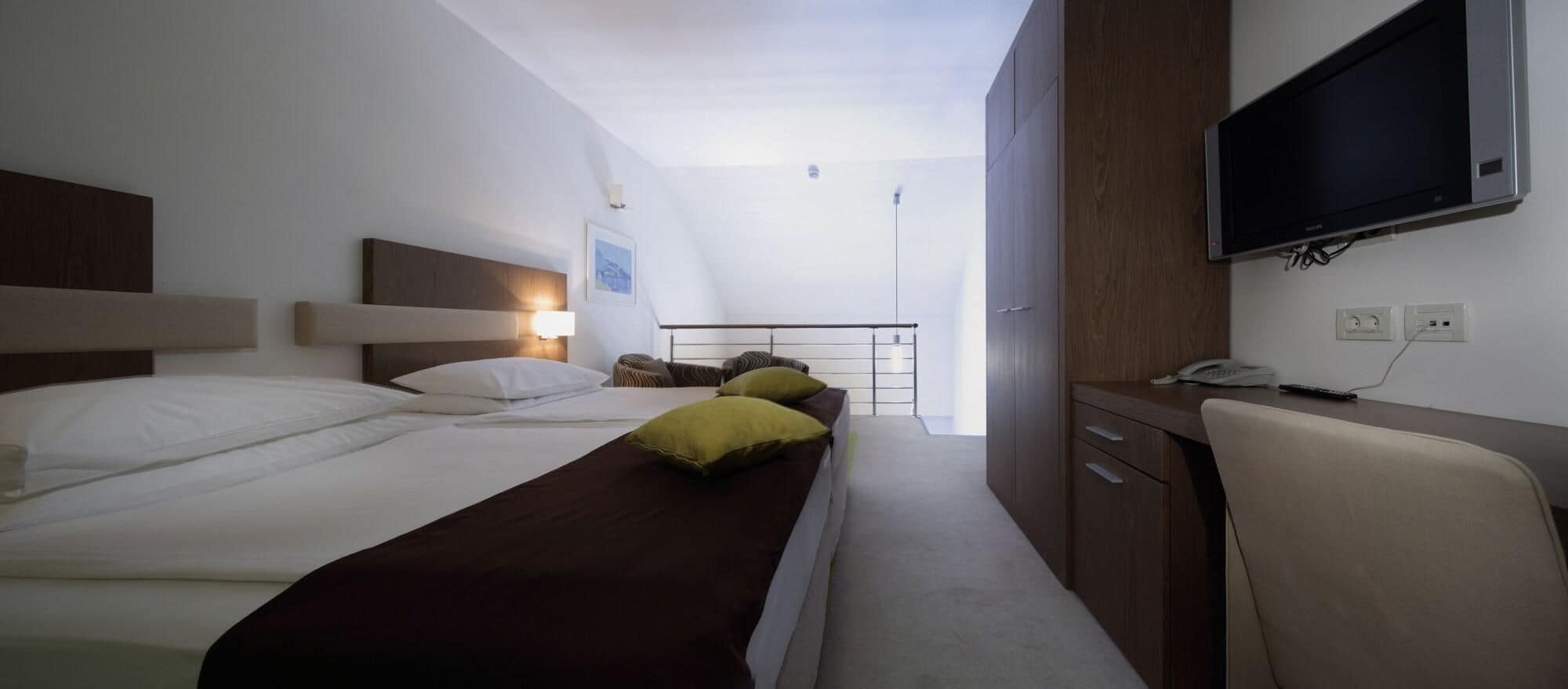 Habitación de hotel con dos camas, un escritorio con silla, televisor y teléfono.