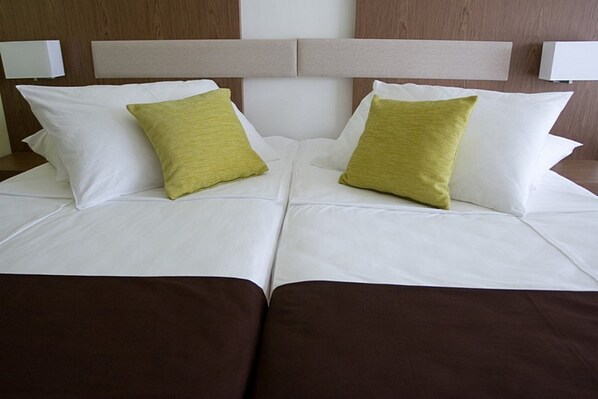A double bed with white bedding and two green pillows. - Hotel Park Makarska (Makarska)