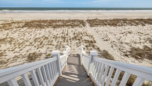 Eine Holztreppe führt zu einem Strand mit freiem Blick auf den Ozean.
