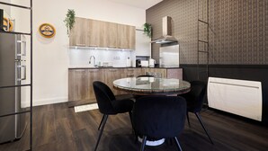 A modern kitchen with wooden cabinets, a round glass table, and black chairs. - La Suite Urbaine - Place d'Erlon - Bulle de Calme (Reims)