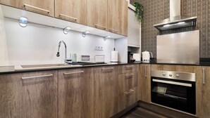 A modern kitchen with wooden cabinets, stainless steel appliances, and a built-in oven. - La Suite Urbaine - Place d'Erlon - Bulle de Calme (Reims)